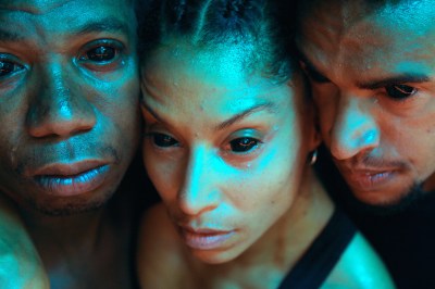 A close up of three dark-skinned people with huge, dialated pupils.