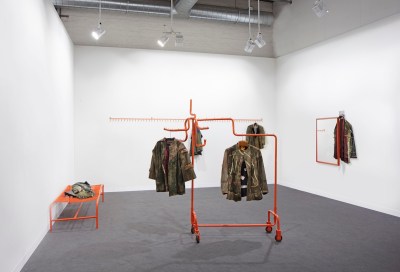 An installation composed of coats hanging on an orange armature.