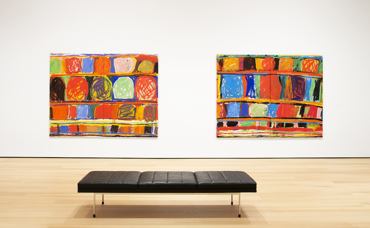 A bench beneath two abstract paintings composed of rows of scrawled circles.