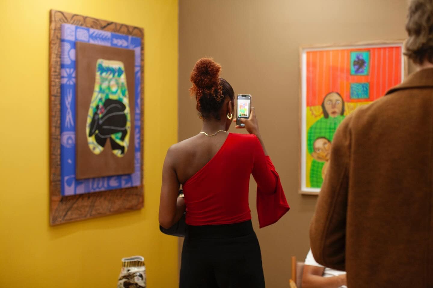 A woman takes a photo of an artwork at an art fair.