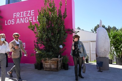 People walk by a bright pink banner labeled Frieze Los Angeles 2022.