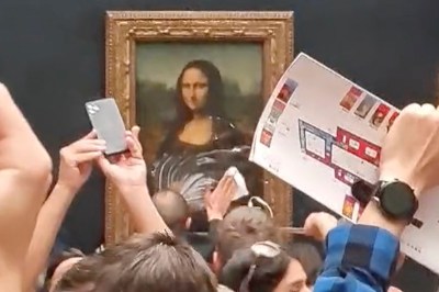 Museum visitors photographing a portrait of a woman that has been smeared with cake.