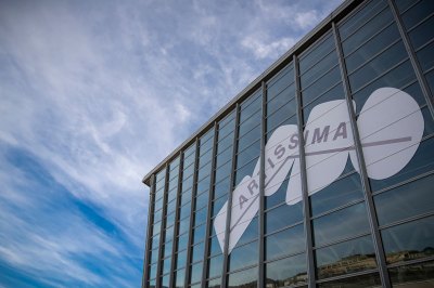 View of a glass building bearing a vinyl sign reading Artissima, a cloudy sky in the background.