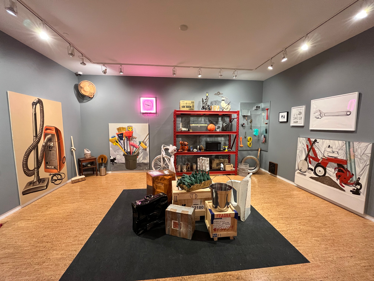 An exhibition space made to look like a utility closet, with paintings leaned against its walls and clustered in its center.