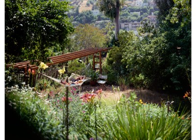 Two women are seen laying in a hammock in a lush green garden.