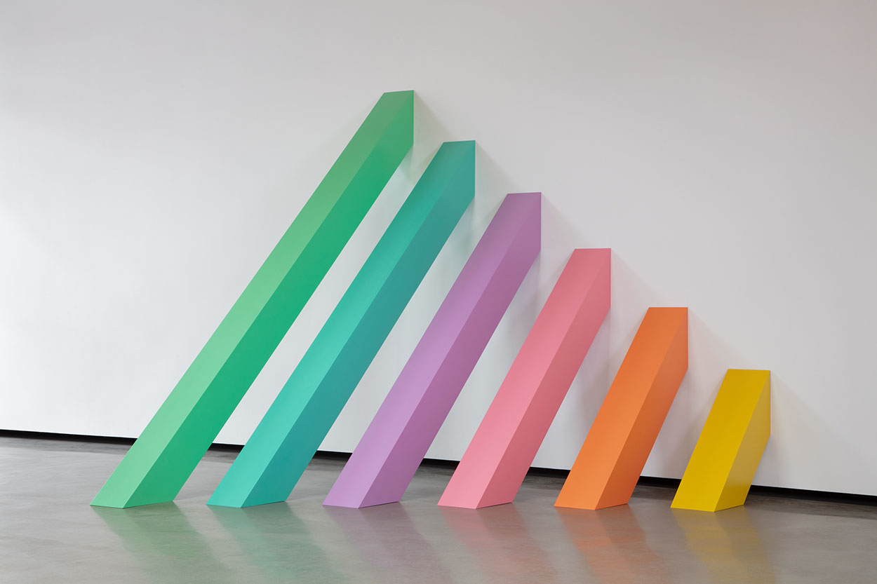 6 rectangular prisms are angled against a wall, descending from largest to smallest, and in a pastel rainbow gradient.