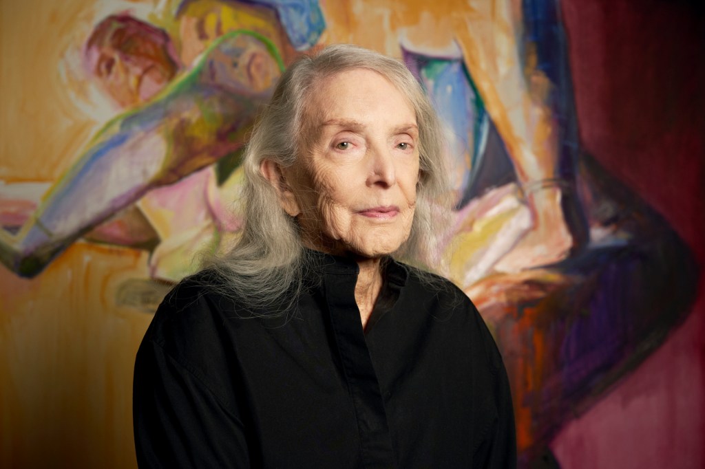 A 90-something white woman with beautiful silver hair and blue eyes is seen in front of an expresive, colorful, double self-portrait that she painted.