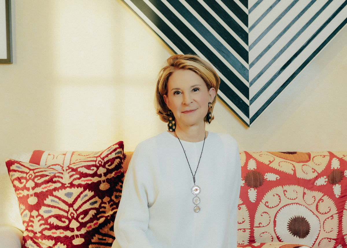 Portrait of Estrellita B. Brodsky, seated on a patterned couch with a Carmen Herrera painting behind her.