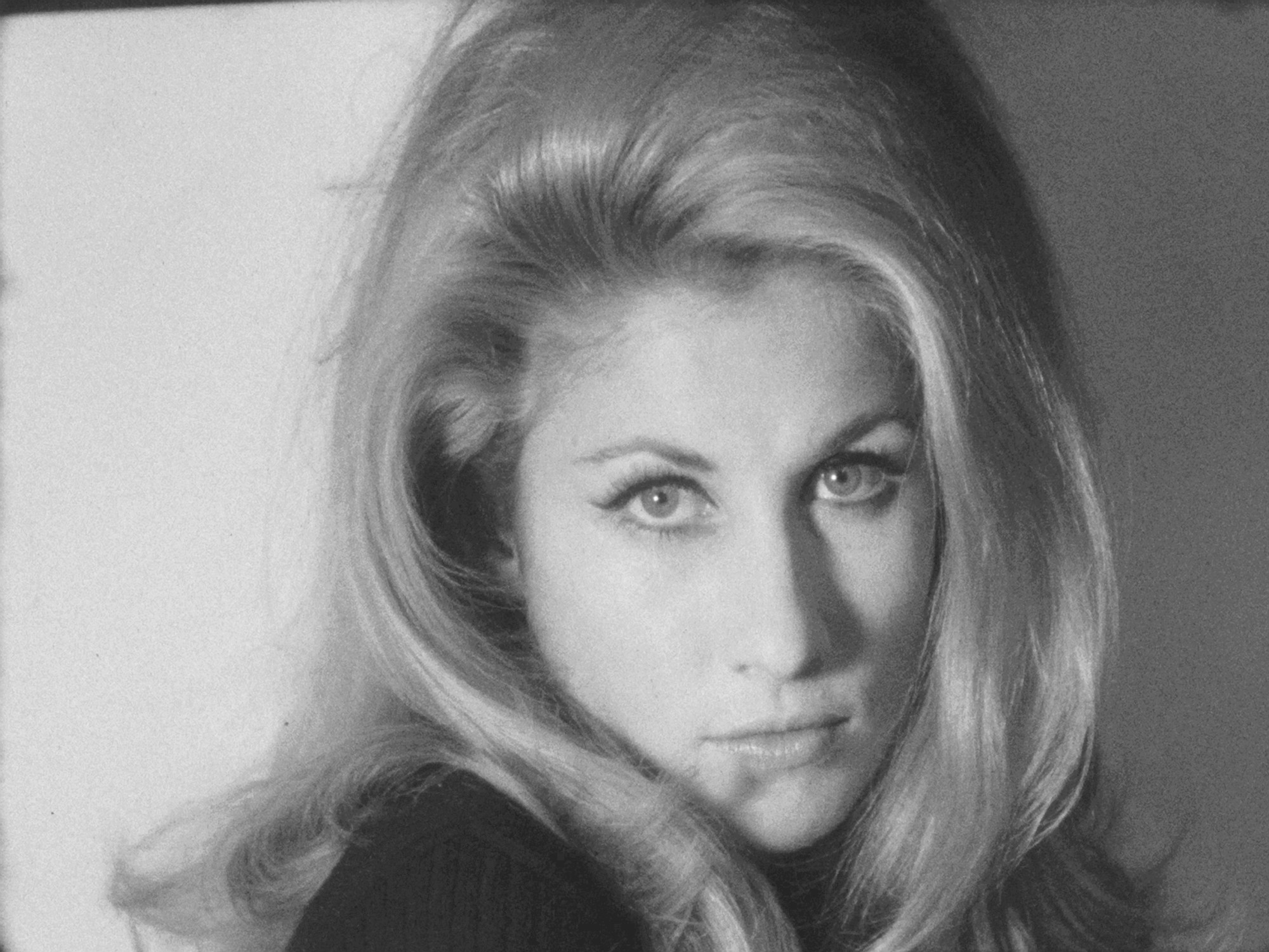 A black-and-white image of a blonde woman with big hair staring intensely at the camera.