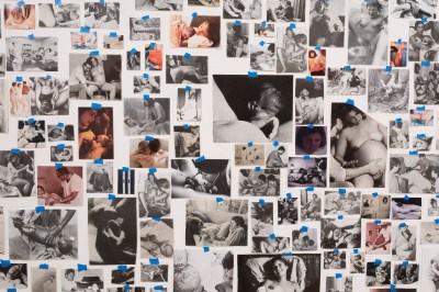 Dozens of images of people giving birth, apparently taken at different points in history, are taped in a haphazard grid with blue tape.