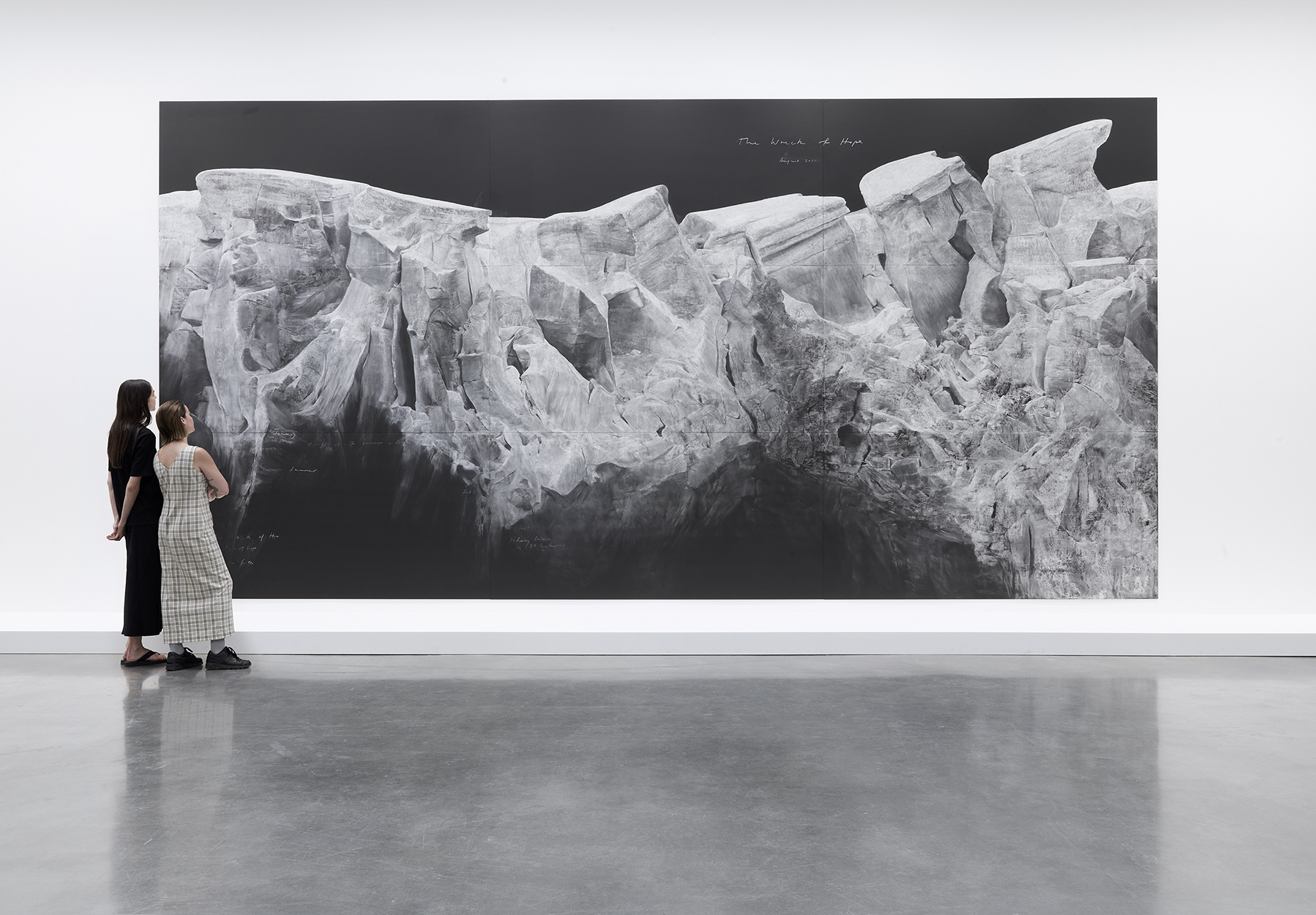 Two people stand in front of a giant drawing of an iceberg.