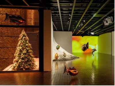 An installation featuring a Christmas tree with a blow-up fish suspended over it.