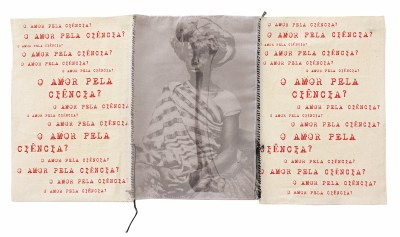 A triptych in which the middle panel is an image of a Black woman superimposed with a bone. Sewn to either side are white panels that repeatedly bear the phrse 'O AMOR PELA CIÊNCIA?'