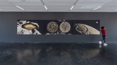 Installation view of a triptych tapestry showing images of the moon.