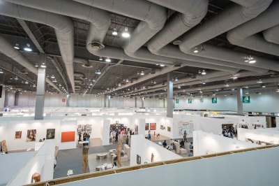 Aerial view of an art fair, showing a convention center with a ceiling of exposed HVAC tubes.